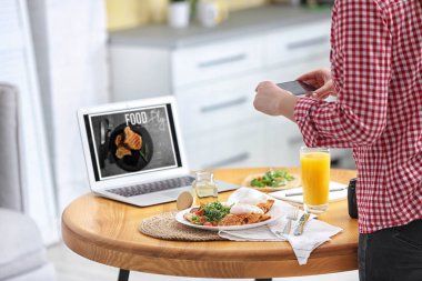 Yemek blogcusu öğle yemeğini içeride, ahşap masada çekiyor.