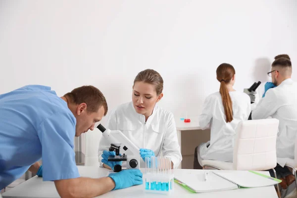 Studenci medycyny pracujący z mikroskopem w nowoczesnym laboratorium — Zdjęcie stockowe