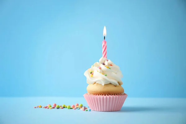 Delicioso cupcake de cumpleaños con vela sobre fondo azul claro —  Fotos de Stock