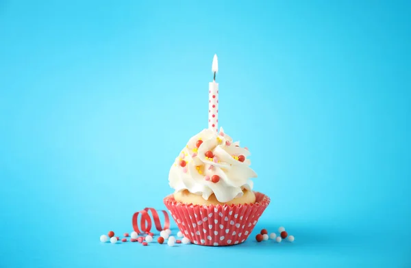 Delicioso cupcake de cumpleaños con vela sobre fondo azul claro —  Fotos de Stock