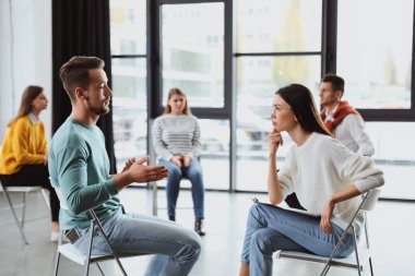 Psychotherapist working with patient in group therapy session indoors