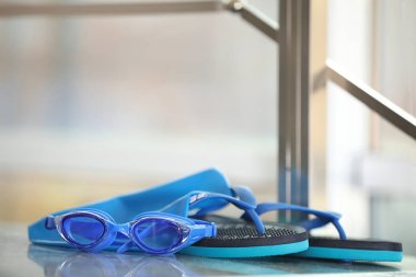 Yüzme şapkası, gözlükler ve arka planda bulanık terlikler. Metin için boşluk