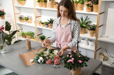 Çiçekçi dükkanda taze çiçeklerle buket yapıyor.