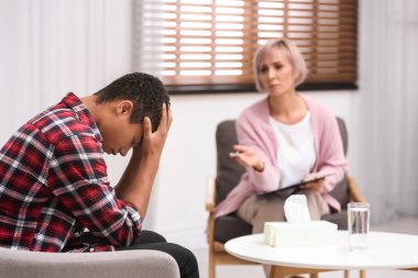 Ofiste Afro-Amerikalı bir çocukla çalışan psikoterapist.