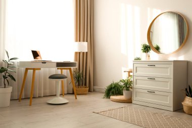 Çekmeceli ve yuvarlak aynalı şık bir oda.