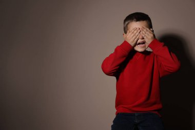 Bej arka planda korkmuş küçük bir çocuk, mesaj için yer var. Yurtiçi 