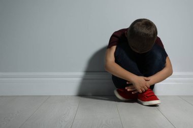 Beyaz duvarın yanında küçük bir çocuk, mesaj için yer var. Aile içi şiddet