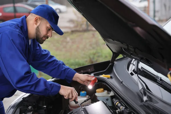 Jovem Mecânico Com Lanterna Fixando Carro Livre — Fotografia de Stock