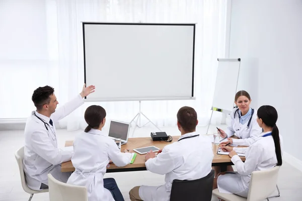 Equipo de médicos que utilizan el proyector de vídeo durante la conferencia en interiores —  Fotos de Stock