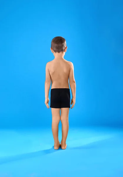 Niño en ropa interior sobre fondo azul claro, vista trasera — Foto de Stock