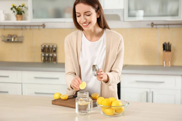 Young woman making lemon water in kitchen