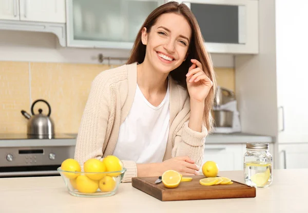 Mujer joven haciendo agua de limón en la cocina — Foto de Stock