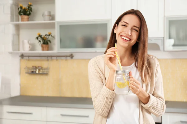 Mujer joven con tarro de masón de agua de limón en la cocina — Foto de Stock