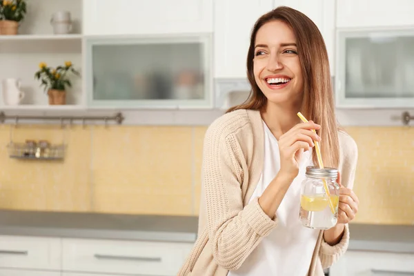 Mujer joven con tarro de masón de agua de limón en la cocina — Foto de Stock