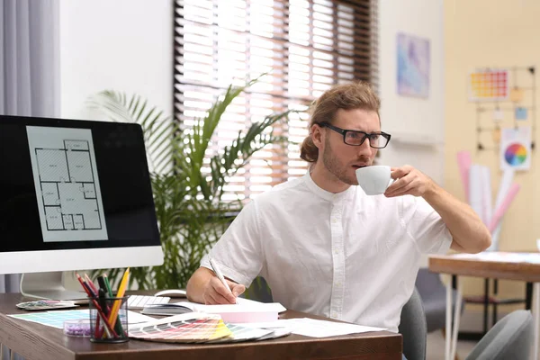 プロのインテリアデザイナーがオフィスの職場でコーヒーを飲む — ストック写真