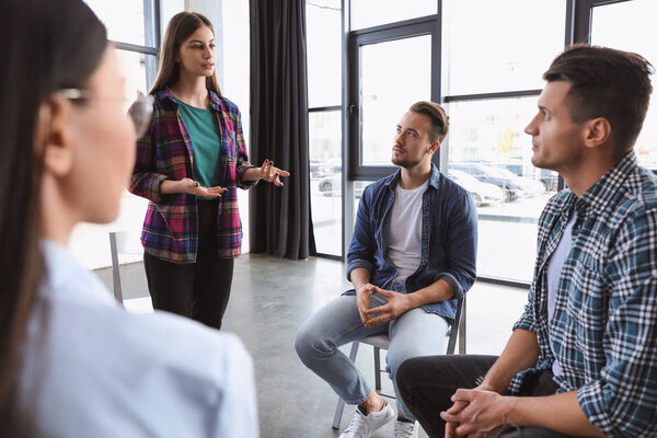Psychotherapist working with patients in group therapy session indoors