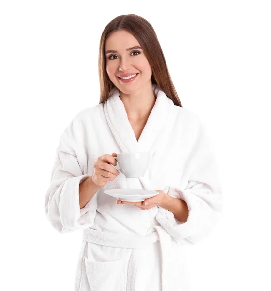 Young woman in bathrobe with cup of drink on white background — ストック写真