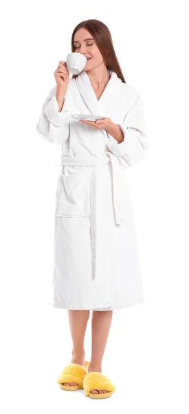 Jonge vrouw in badjas met kopje drank op witte achtergrond — Stockfoto