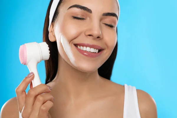 Mujer Joven Usando Cepillo Limpieza Facial Sobre Fondo Azul Claro —  Fotos de Stock