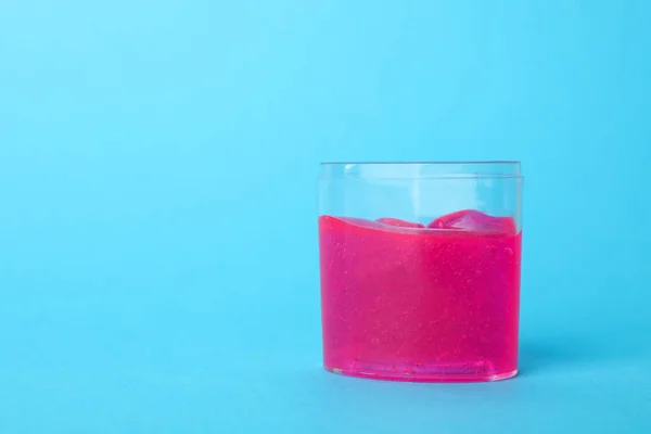 Lodo rosa em recipiente de plástico sobre fundo azul claro. Espaço — Fotografia de Stock