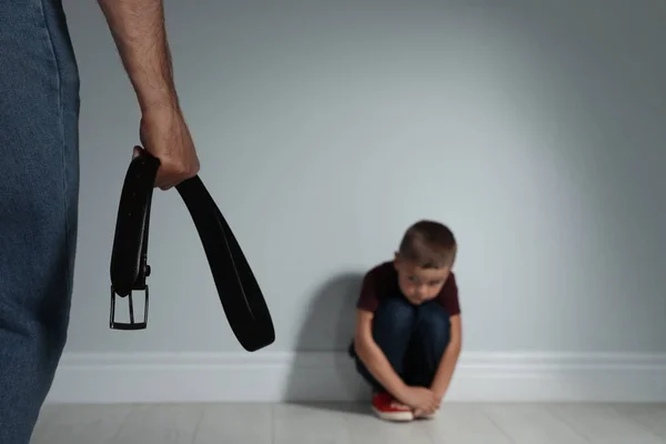 Um homem a ameaçar o filho com cinto dentro de casa. Violência doméstica — Fotografia de Stock