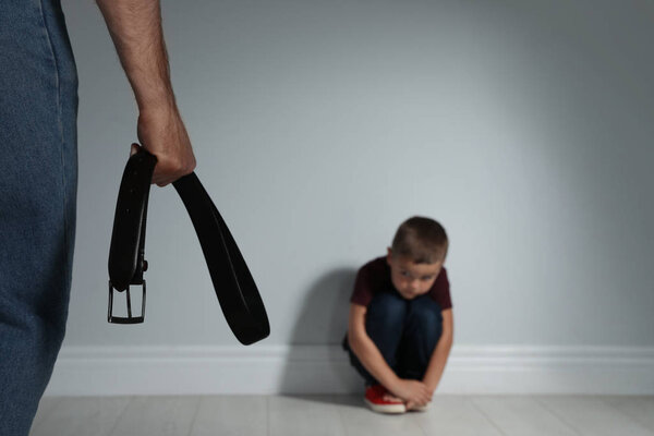 Man threatening his son with belt indoors. Domestic violence con