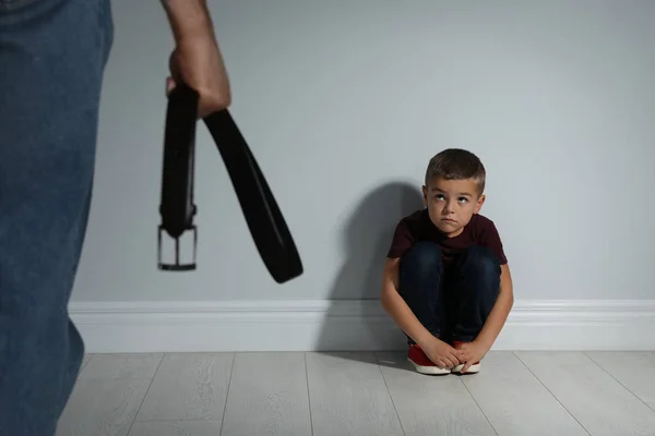 Un uomo che minaccia suo figlio con la cintura in casa. Violenza domestica — Foto Stock