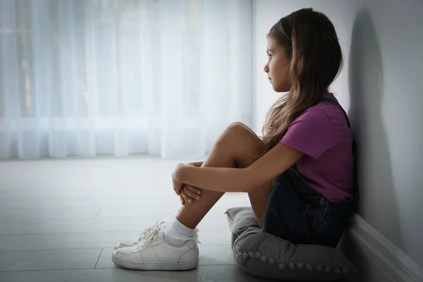 Trauriges kleines Mädchen in der Nähe weißer Wände drinnen, Platz für Text. domesti — Stockfoto