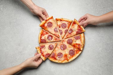 İnsanlar açık gri masada leziz biberli pizza dilimleri yiyorlar.