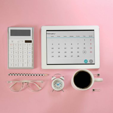 Pembe zemin üzerinde takvim uygulaması olan modern tablet, düz uzanma