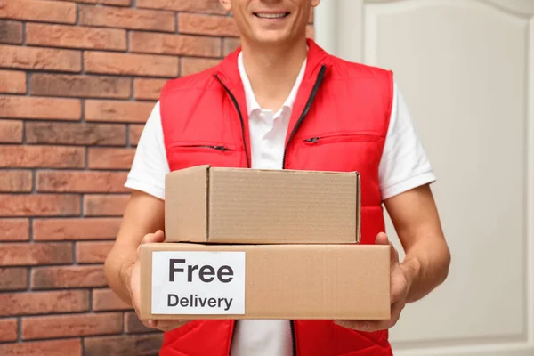 Курьер держит посылки с наклейкой Бесплатная доставка в помещении, заглушки — стоковое фото