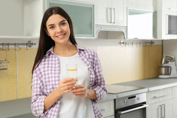Bella giovane donna con acqua di limone in cucina — Foto Stock