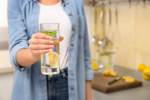 Mujer joven con vaso de agua de limón en la cocina, primer plano. Espacio — Foto de Stock