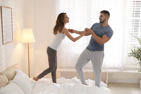 Schönes junges Paar tanzt zu Hause auf dem Bett — Stockfoto