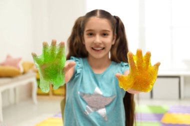 Preteen girl with slime in playroom, focus on hands clipart