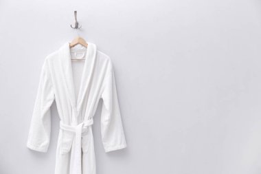 Açık renkli duvarda asılı beyaz bornoz. Metin için boşluk
