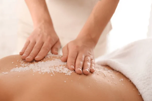 Jovem mulher tendo procedimento de limpeza corporal com sal marinho no spa — Fotografia de Stock