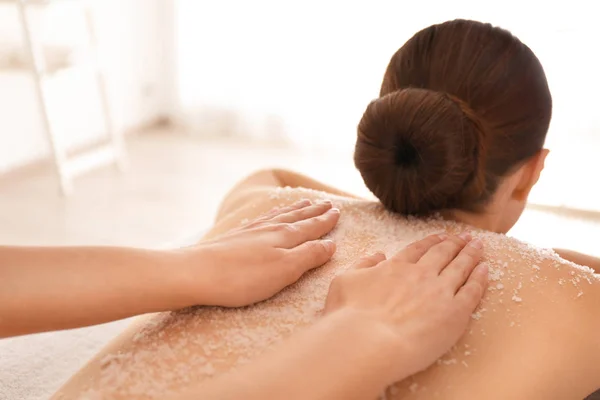 Jovem mulher tendo procedimento de limpeza corporal com sal marinho no spa — Fotografia de Stock