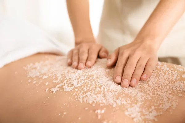 Jovem mulher tendo procedimento de limpeza corporal com sal marinho no spa — Fotografia de Stock