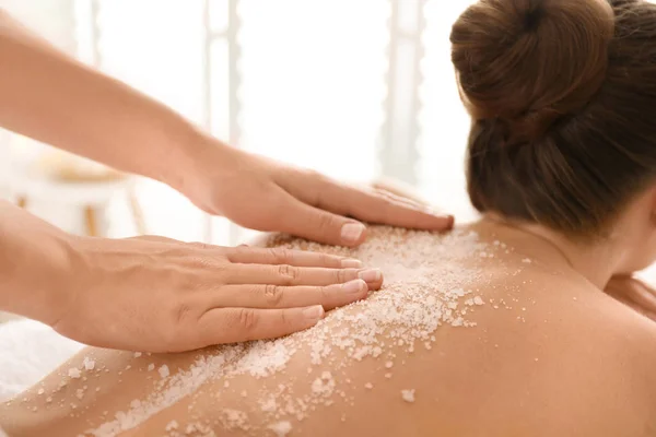 Jovem mulher tendo procedimento de limpeza corporal com sal marinho no spa — Fotografia de Stock