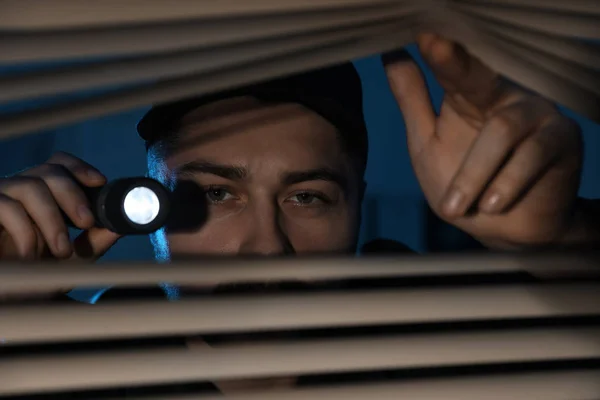 Manlig Säkerhetsvakt Med Ficklampa Tittar Genom Fönsterpersienner Mörker — Stockfoto