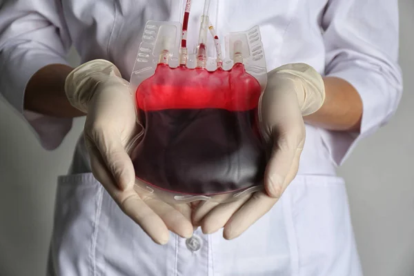 軽い灰色の背景で輸血のための血液を保持する女性 クローズアップ 寄付の考え方 — ストック写真