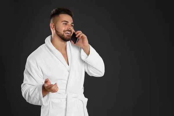 Ung man i badrock pratar på mobiltelefon mot svart rygg — Stockfoto
