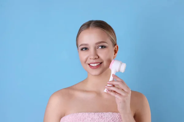 Giovane donna che lava il viso con spazzola detergente sulla schiena azzurra — Foto Stock