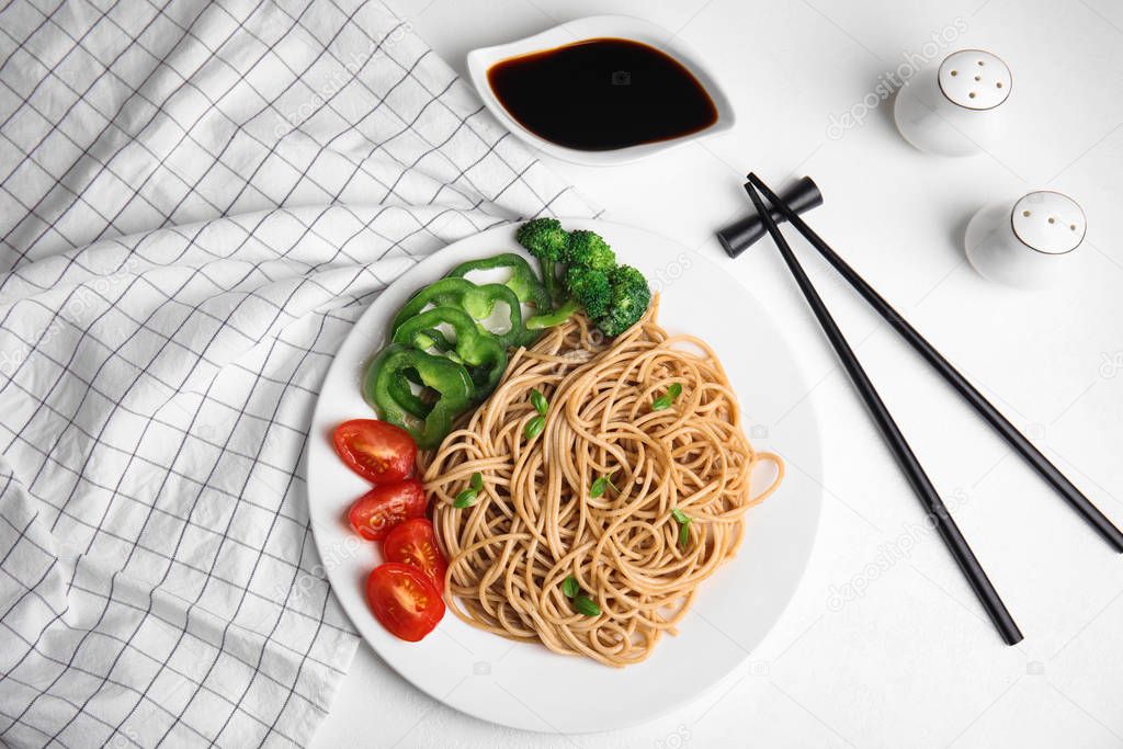 Tasty buckwheat noodles with fresh vegetables served on white table, flat lay