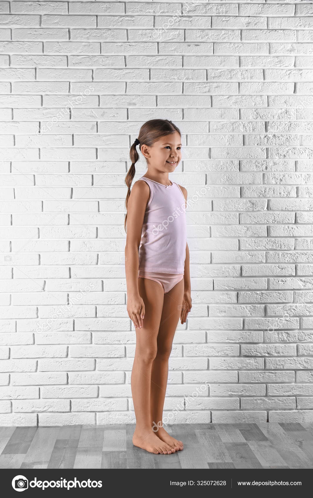 Cute little girl in underwear near white brick wall Stock Photo by  ©NewAfrica 325072628