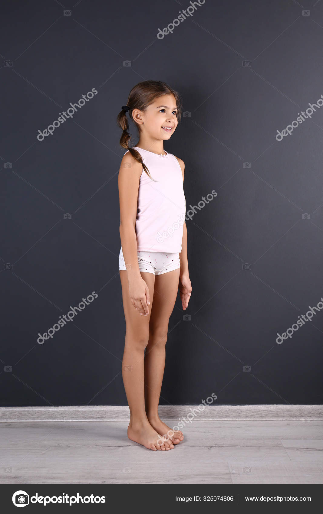 Cute little girl in underwear near dark wall Stock Photo by