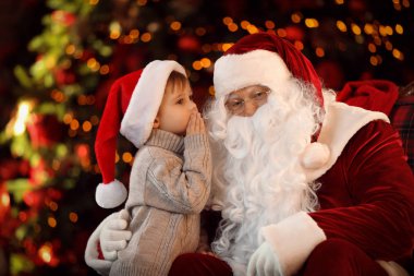Noel Baba ve küçük çocuk Noel ağacının yanında.
