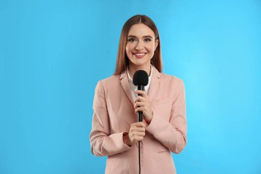 Mavi arka planda mikrofonu olan genç bayan gazeteci.