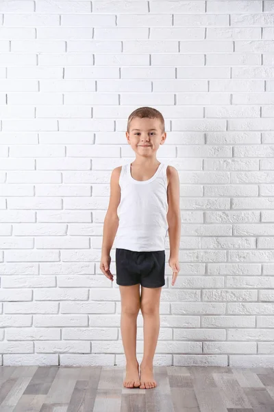 Lindo niño en ropa interior cerca de la pared de ladrillo blanco — Foto de Stock